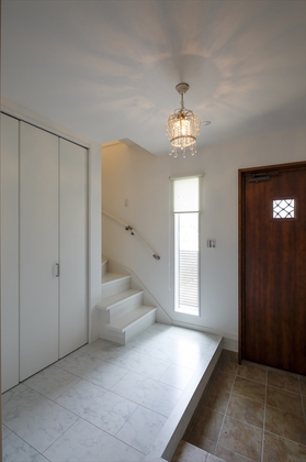 子世帯の玄関は大理石調フローリングに建具も白で統一。シューズクローゼットとは別に大容量の収納も確保。